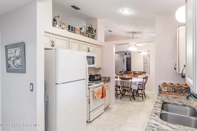 a kitchen with stainless steel appliances a refrigerator a sink a stove and white cabinets