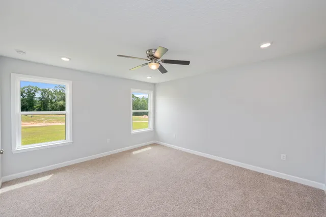 an empty room with windows and ceiling fan