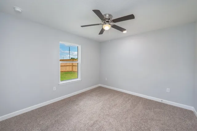 a view of an empty room and ceiling fan