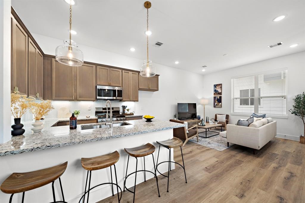 a kitchen with stainless steel appliances granite countertop a stove top oven a sink dishwasher a dining table and chairs with wooden floor