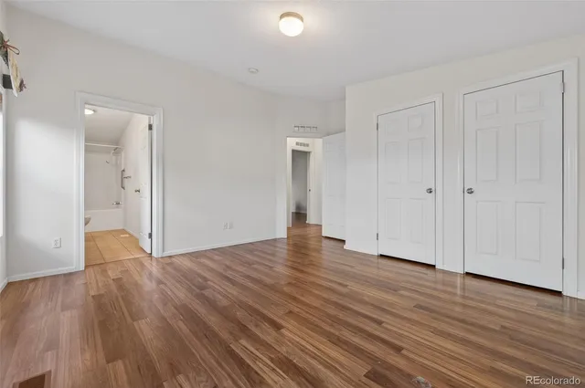 a view of an empty room with wooden floor and closet