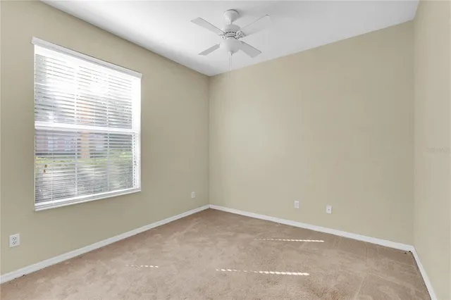 an empty room with a window and a fan