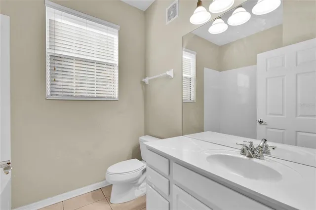 a bathroom with a granite countertop sink toilet a large mirror and a window