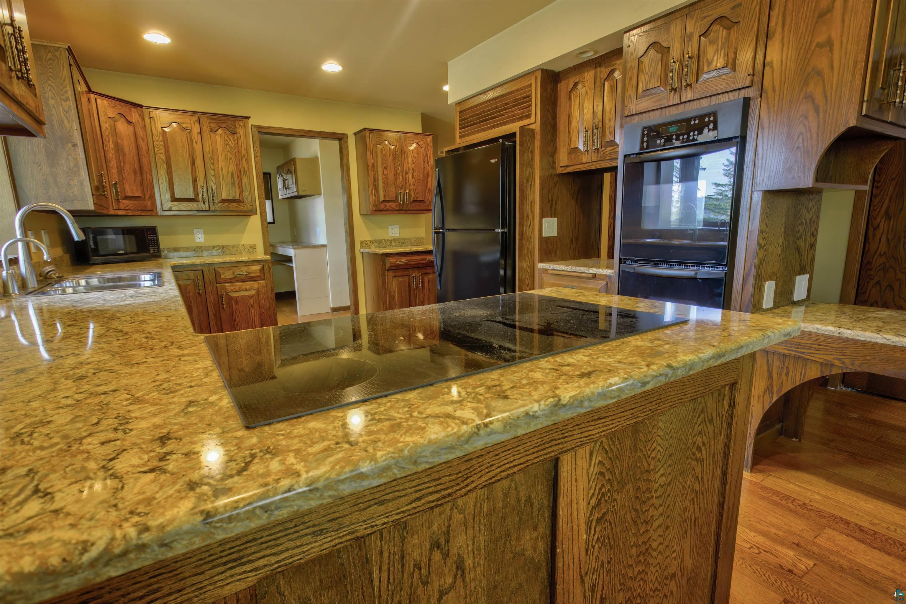 1933 West Shagawa Road Ely, MN 55731 - Photo 12 of 46 Kitchen with light stone countertops, black appliances, sink, and light wood-type flooring