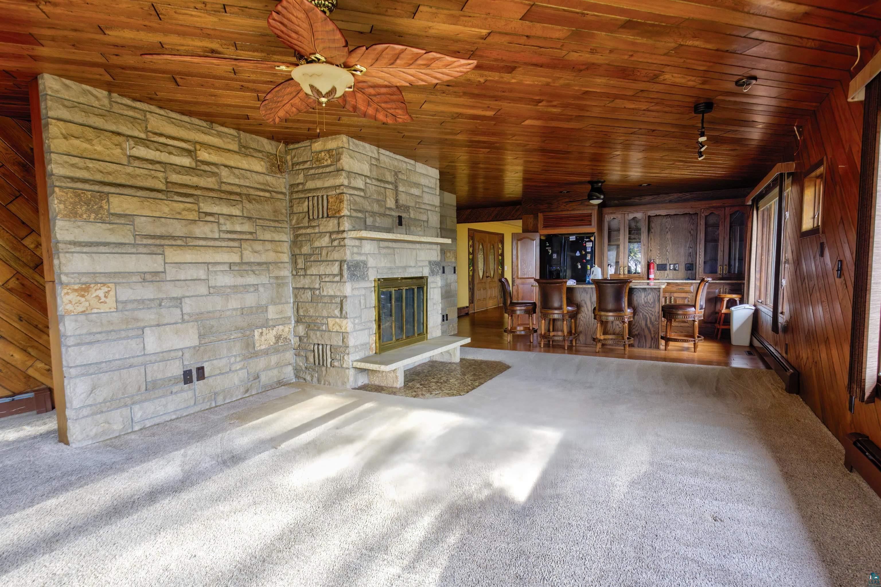 1933 West Shagawa Road Ely, MN 55731 - Photo 4 of 46 Unfurnished living room featuring ceiling fan, wood walls, wooden ceiling, and a baseboard heating unit