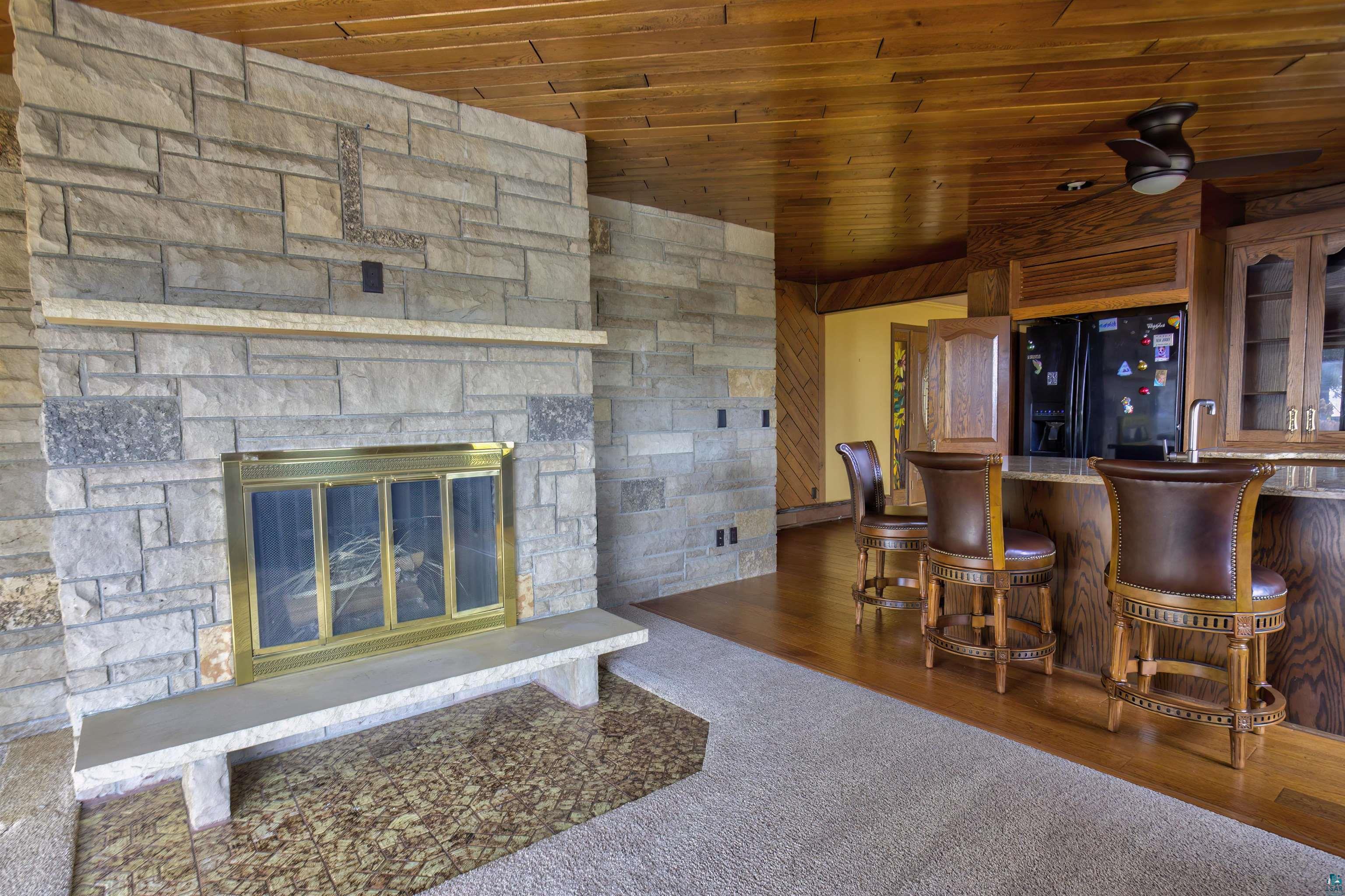 1933 West Shagawa Road Ely, MN 55731 - Photo 6 of 46 Bar featuring a fireplace, wood ceiling, black refrigerator with ice dispenser, ceiling fan, and dark hardwood / wood-style floors
