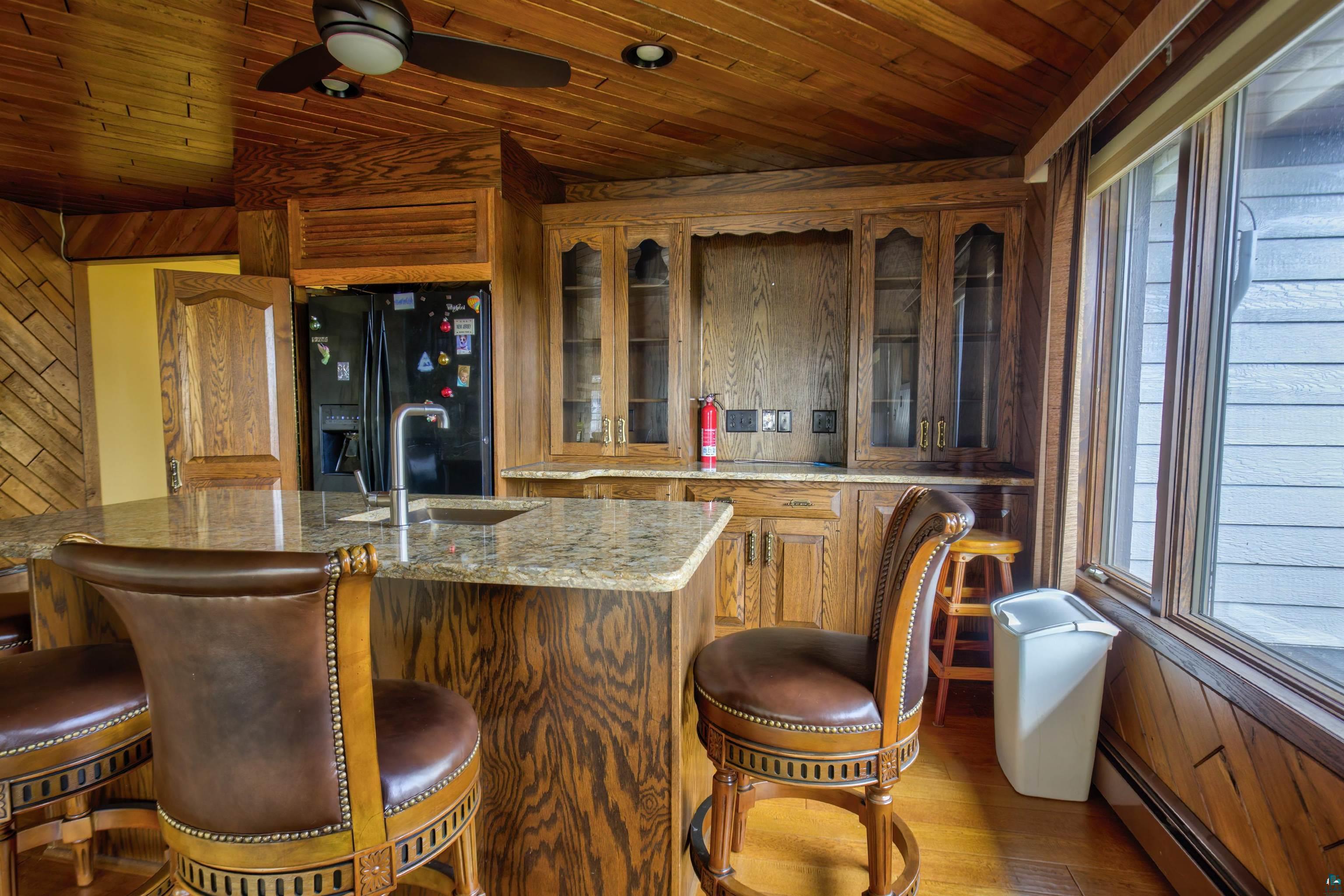 1933 West Shagawa Road Ely, MN 55731 - Photo 7 of 46 Bar featuring a wealth of natural light, wooden walls, black refrigerator with ice dispenser, and wooden ceiling