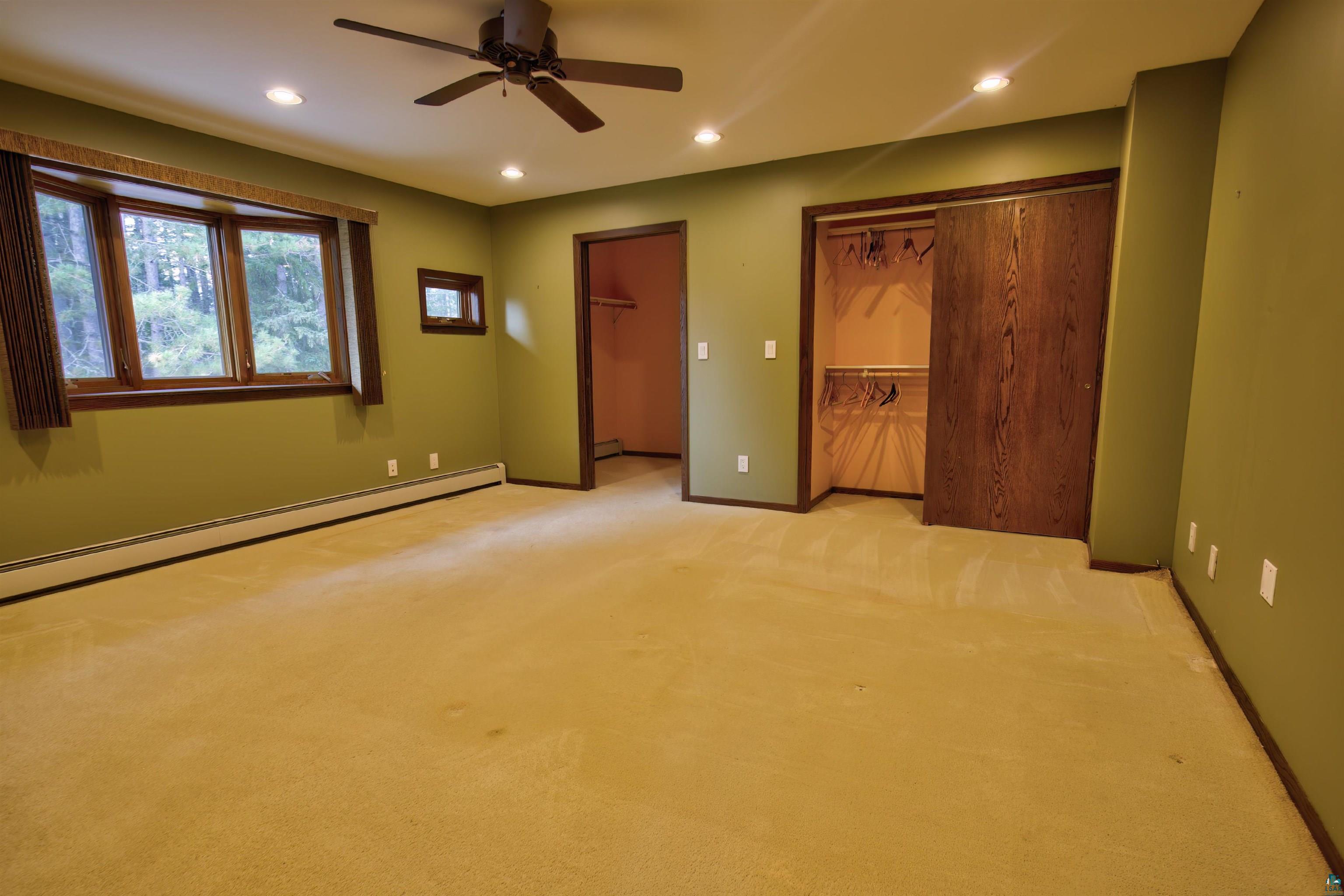 1933 West Shagawa Road Ely, MN 55731 - Photo 10 of 46 Unfurnished bedroom featuring light carpet, baseboard heating, a walk in closet, and ceiling fan