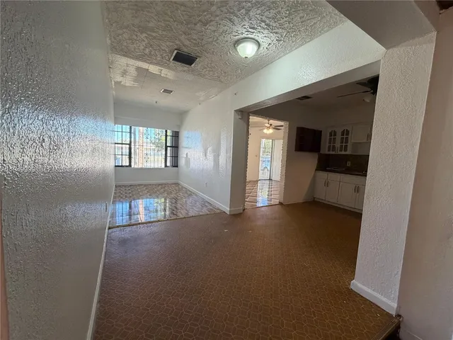 a view of a hallway with wooden floor and a living room