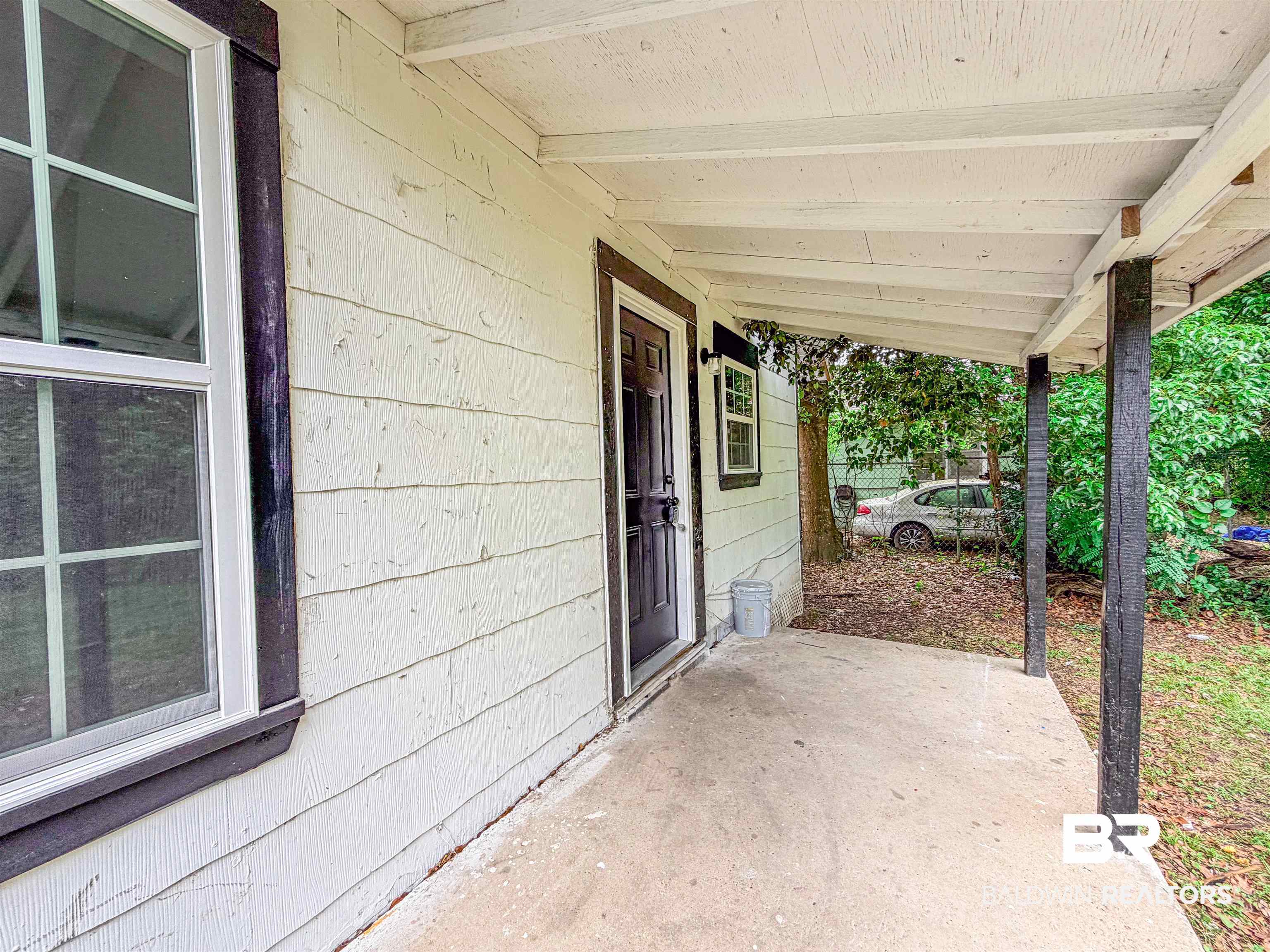 38 Flock Avenue Mobile, AL 36610 - Photo 23 of 27 Covered concrete porch with white paneled siding and dark trim accents