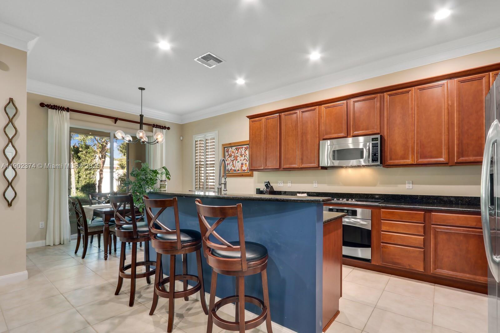 1053 Big Pine Way Jupiter, FL 33458 - Photo 11 of 48 a kitchen with stainless steel appliances granite countertop wooden cabinets a dining table and chairs