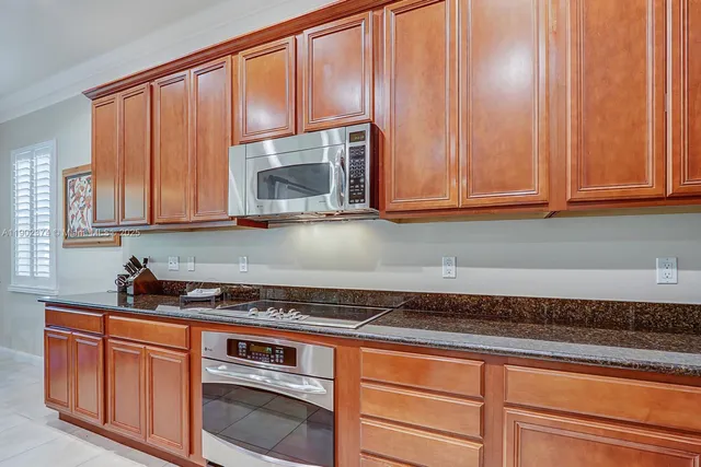 a kitchen with granite countertop cabinets stainless steel appliances a sink and window
