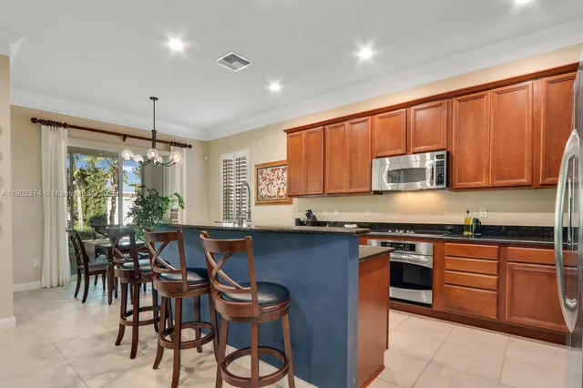a kitchen with stainless steel appliances granite countertop wooden cabinets a table and chairs