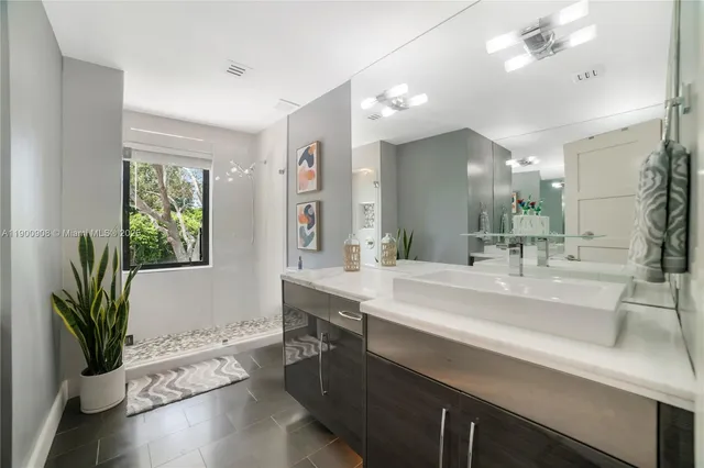 a spacious bathroom with a sink a large mirror and a potted plant