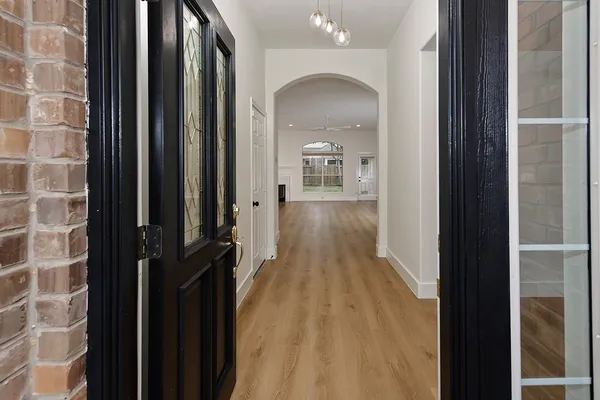 a view of a hallway with wooden floor and a bathroom