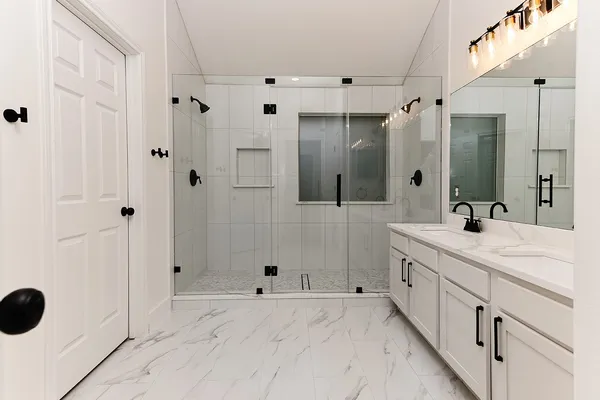 a bathroom with a double vanity sink a large mirror and shower