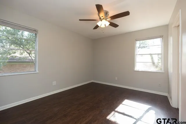 a view of a big room with wooden floor and windows