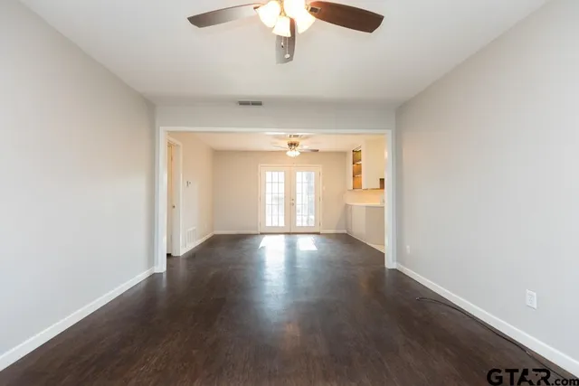 an empty room with wooden floor and windows