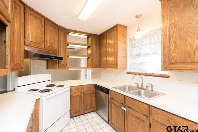 a kitchen with granite countertop a sink appliances cabinets and a counter top space