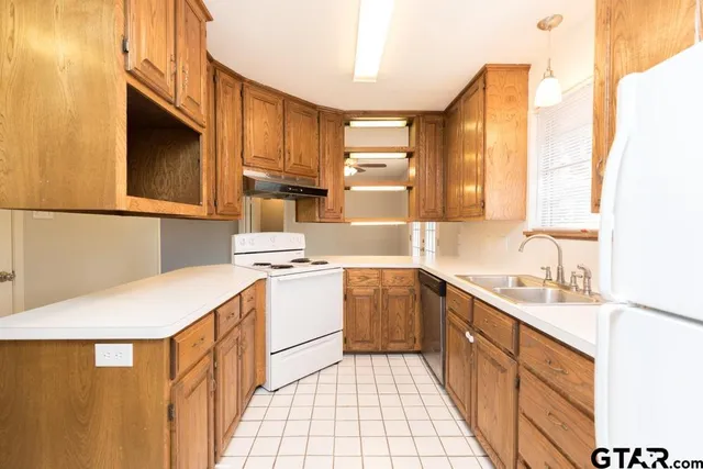 a kitchen with a sink a stove top oven and white cabinets