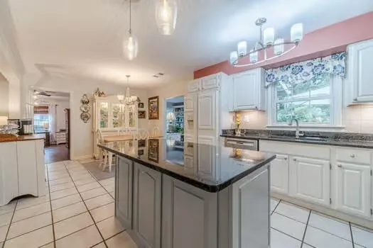 a kitchen with kitchen island granite countertop a sink and refrigerator