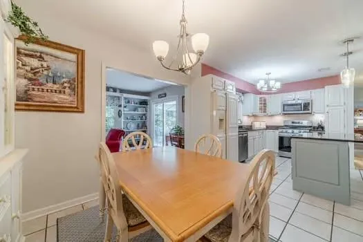 a dining room with wooden floor a chandelier a wooden table and chairs
