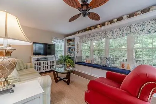 a living room with furniture a ceiling fan and a flat screen tv