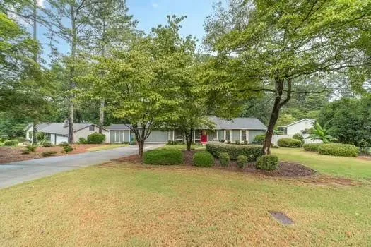 a front view of a house with a garden and trees