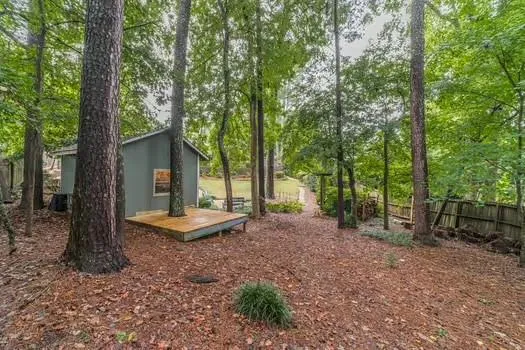 a view of a backyard with table and chairs potted plants and large tree