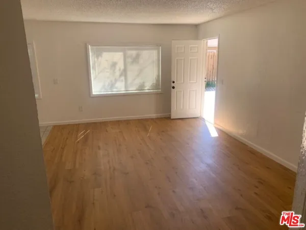 an empty room with wooden floor cabinet and windows