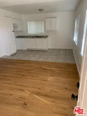a view of kitchen and empty room with wooden floor