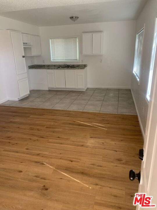 11560 Sage Street Adelanto, CA 92301 - Photo 6 of 18 a view of kitchen and empty room with wooden floor