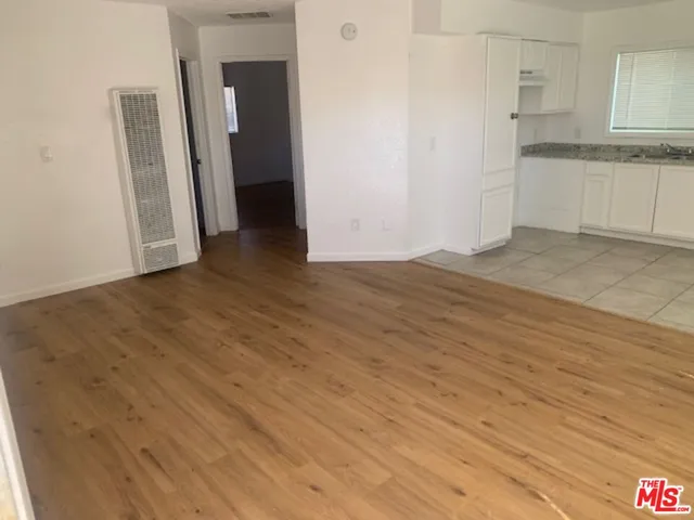 an empty room with wooden floor and white cabinet