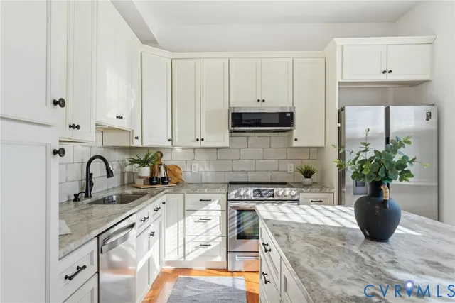 a kitchen with stainless steel appliances granite countertop a sink a stove and a refrigerator