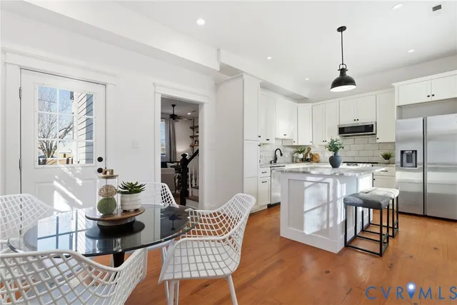 a kitchen with stainless steel appliances kitchen island granite countertop a dining table chairs refrigerator and sink