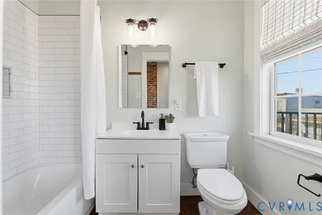 a bathroom with a toilet a sink a mirror a bathtub and vanity