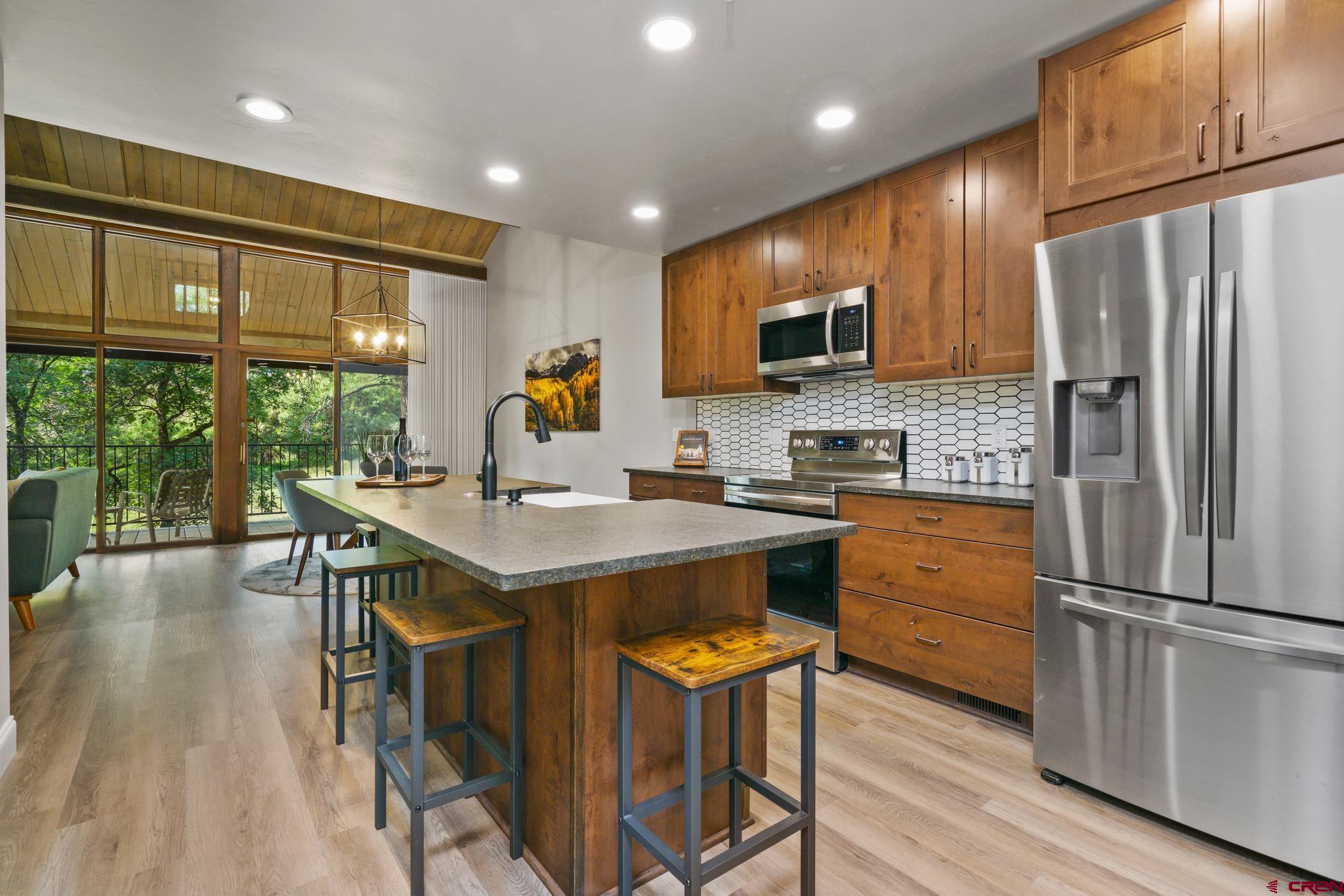 a kitchen with stainless steel appliances granite countertop a refrigerator a stove top oven a sink dishwasher and white cabinets with wooden floor