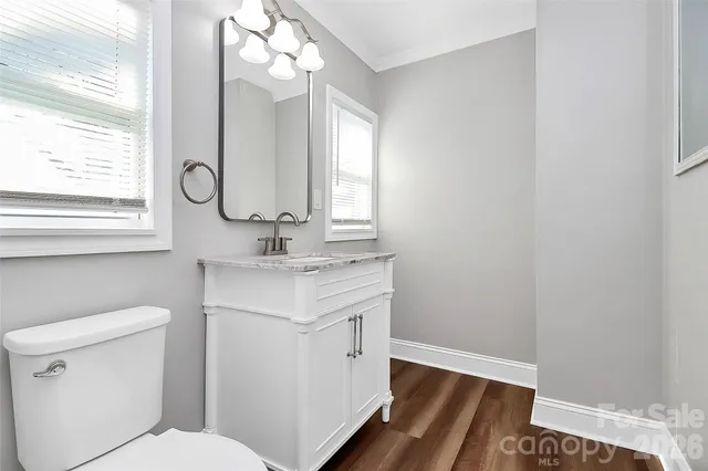 a bathroom with a sink a toilet a mirror and a window