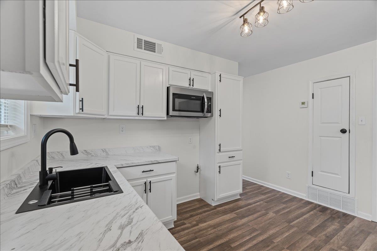 3065 Sax Road Memphis, TN 38109 - Photo 2 of 17 Modern kitchen featuring white cabinetry with matte black hardware, a stainless steel microwave, and wood-finish flooring