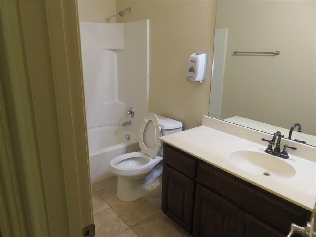 1122 Walter Stephenson Road Midlothian, TX 76065 - Photo 15 of 26 Bathroom featuring a dark wood-finish vanity with an integrated sink, a large wall mirror, and a white bathtub with an overhead shower