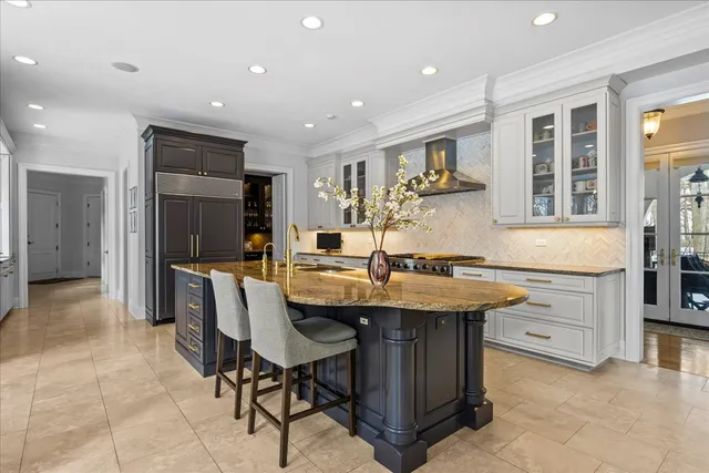 a kitchen with a stove a sink a refrigerator and chairs