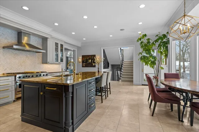 a kitchen with stainless steel appliances granite countertop a stove top oven a dining table and chairs with wooden floor