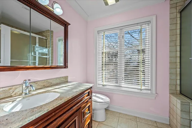 a bathroom with a granite countertop sink a toilet a mirror and a window