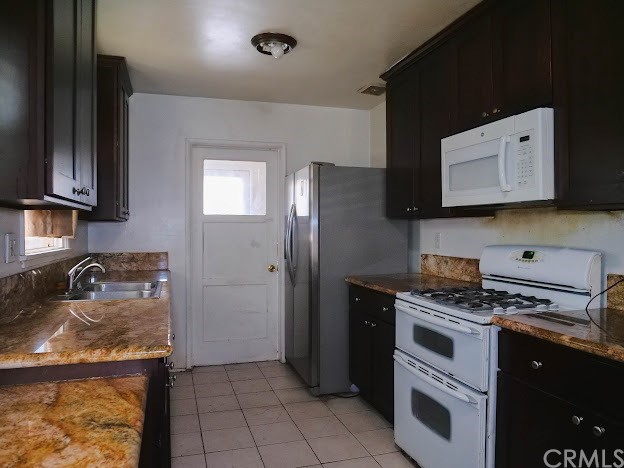 4613 Dunrobin Avenue Lakewood, CA 90713 - Photo 12 of 30 a kitchen with granite countertop a stove top oven cabinetry and refrigerator