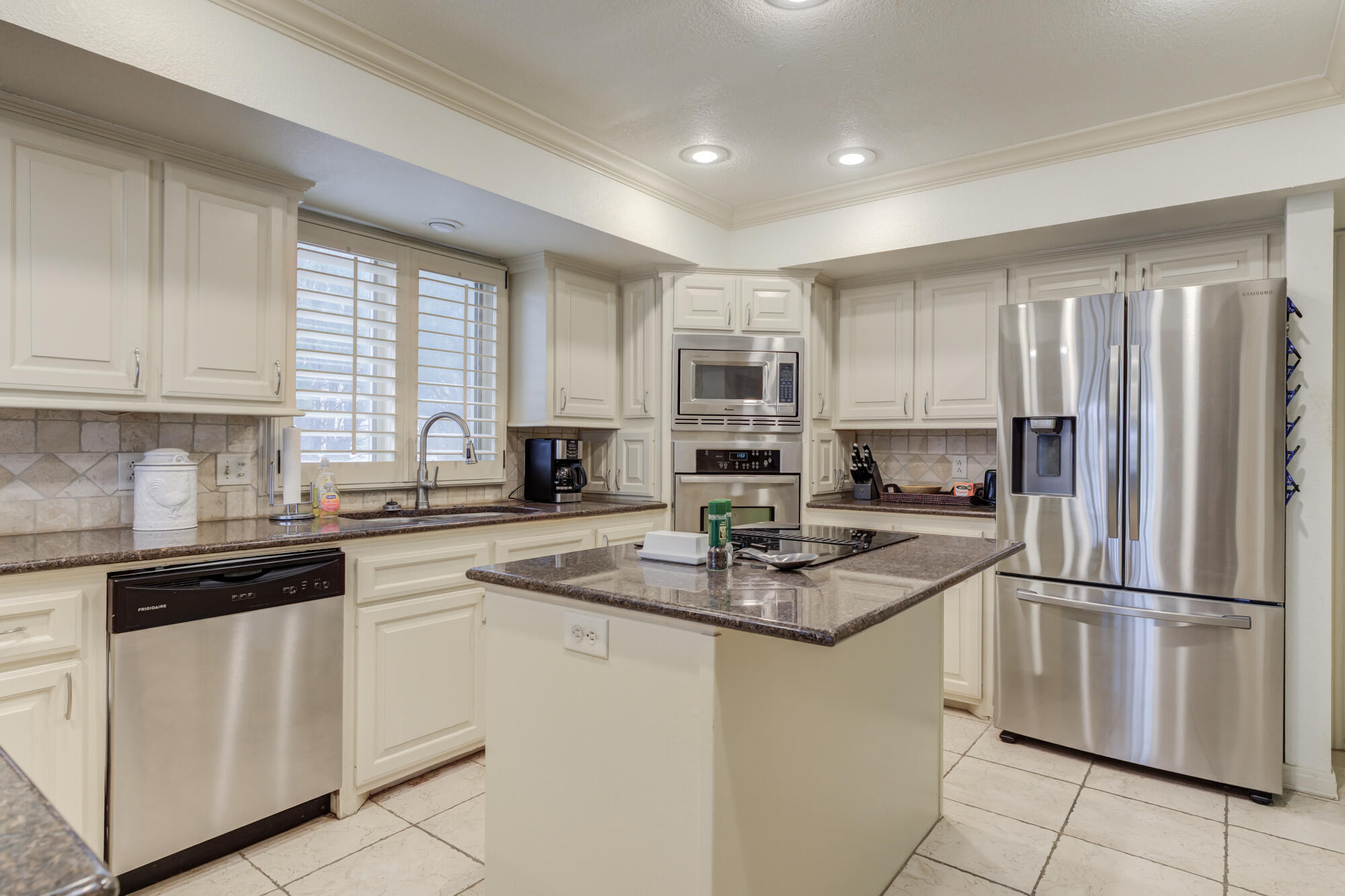 4405 89th Street Lubbock, TX 79424 - Photo 4 of 71 a kitchen with white cabinets and stainless steel appliances