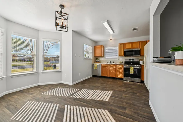 a kitchen with stainless steel appliances granite countertop a stove top oven a sink dishwasher and a refrigerator with wooden floor