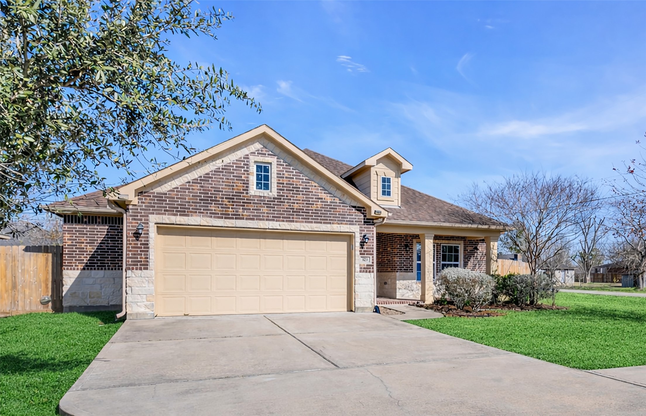 Charming brick-and-stone exterior with a welcoming covered front porch and mature landscaping.VIRTUAL  ENHANCED GRASS