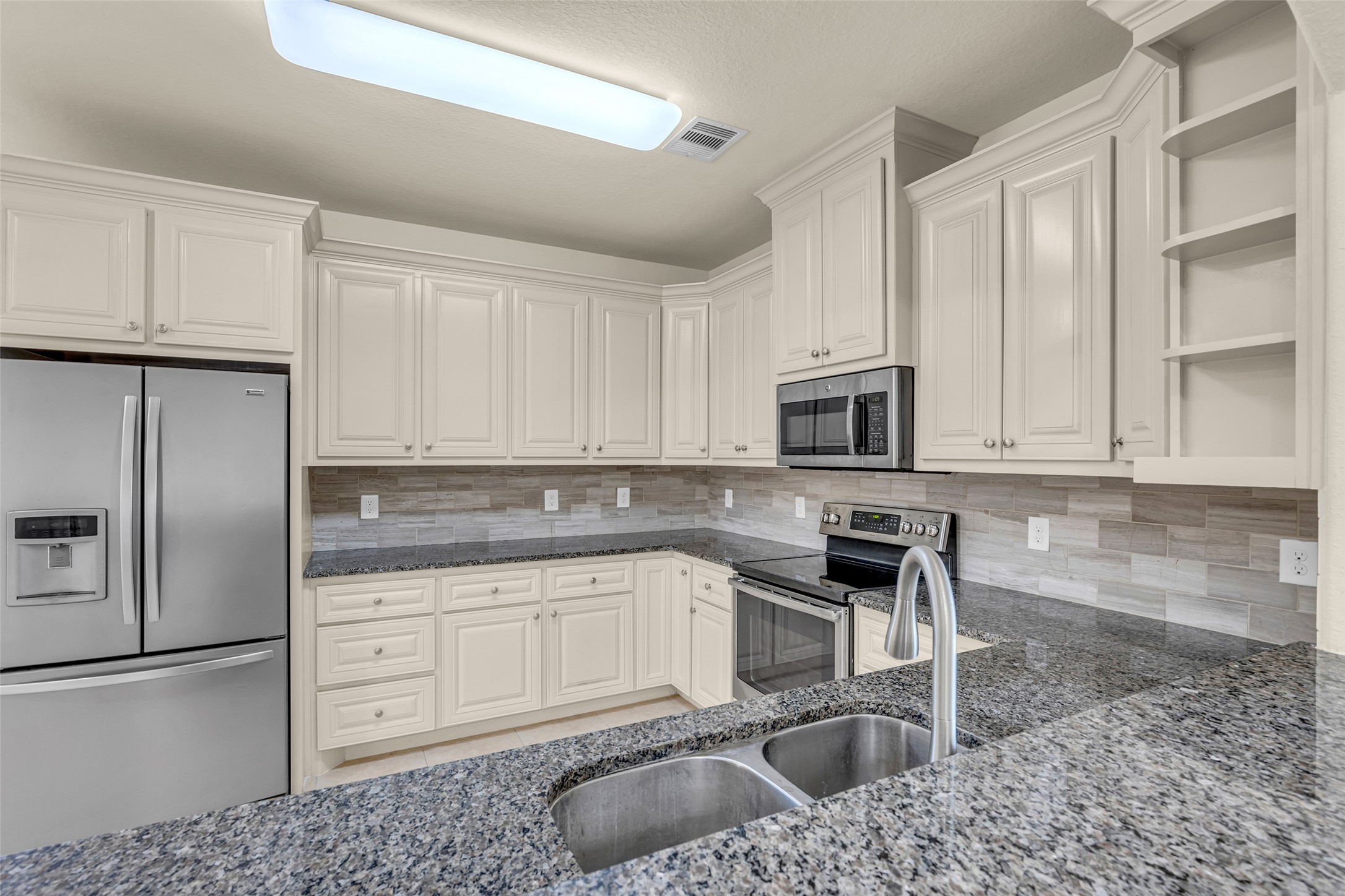 323 Texas Avenue Arcola, TX 77583 - Photo 12 of 27 a kitchen with stainless steel appliances granite countertop a sink a stove a refrigerator and a granite counter tops