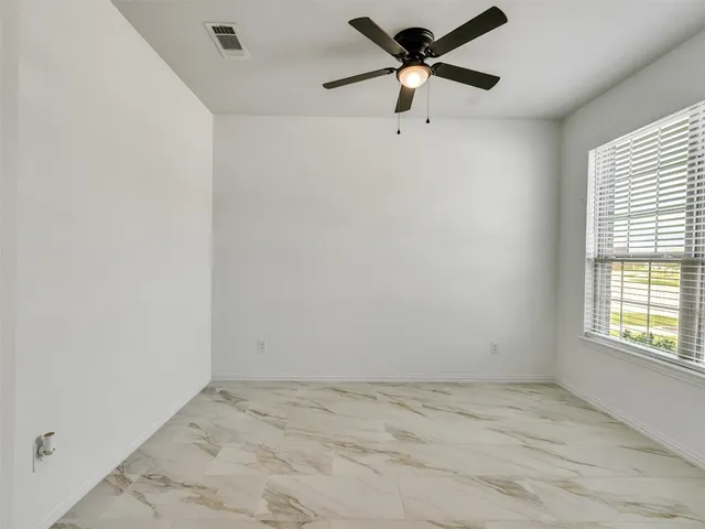 an empty room with a window and a fan