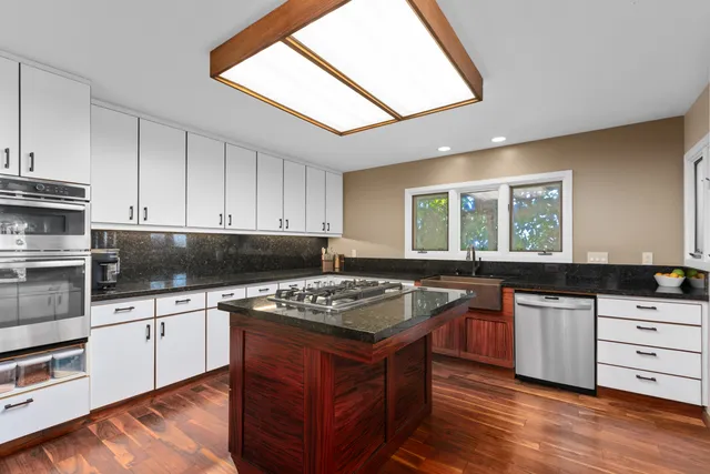 a kitchen with granite countertop a sink stove and cabinets